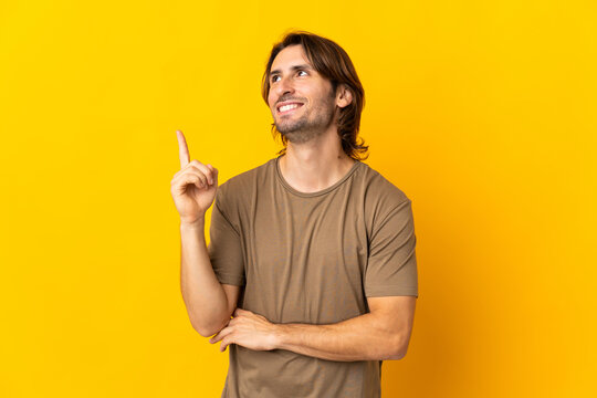 Young handsome man isolated on yellow background pointing up a great idea
