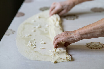 close up of old woman hands making dough with cheese