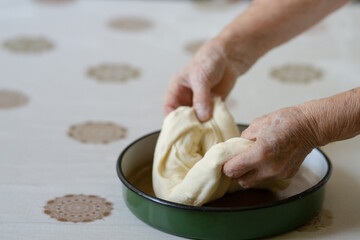 Old woman hands putting stuffed dough in a pan