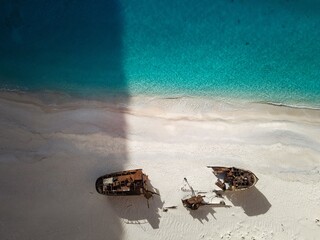 Aerial view of beach shipwrecks on sandy shore with turquoise water.