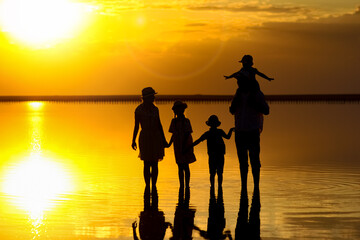 A Happy family silhouette at sea with reflection in park in nature