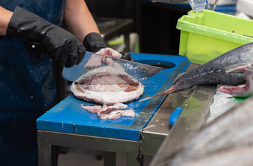 fishmonger cleaning a monk fish for sale