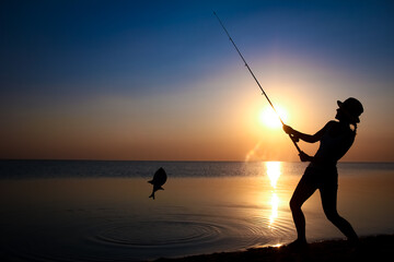 A Happy girl fisherman catches fish by the sea on nature silhouette travel