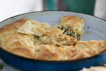 Half eaten baked traditional balkan pie in a pan with filling in the middle