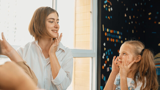 Beautiful teacher teach about body organ while student touching nose. Diverse children doing activity and playing with teacher in classroom. Kid learning, studying at international school. Erudition.