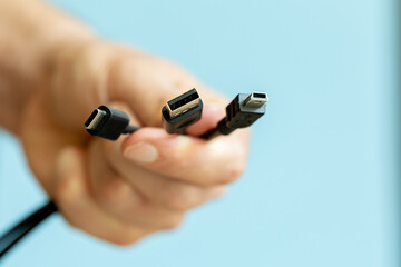 man holding several cables in hand, different types of USB cables, technology and connection  concept
