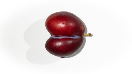 Heart-shaped fruit uncommon because it is two specimens joined by the same stem on a white background with shadow