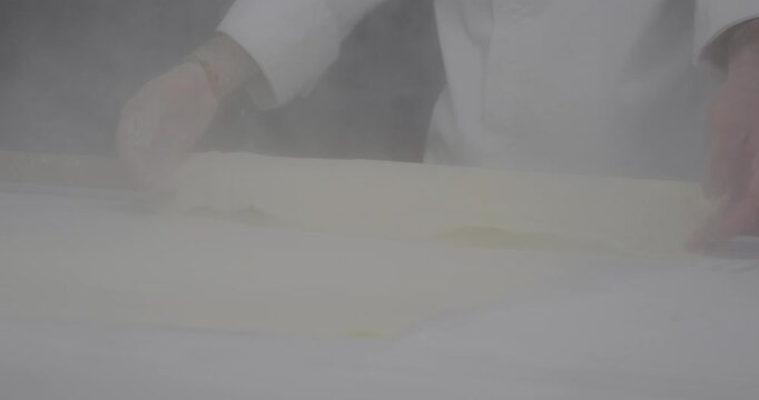 Pastry chef roll out phyllo dough with a rolling pin sprinkle flour. Turkish dessert baklava preparation using traditional recipe. Middle eastern sweets