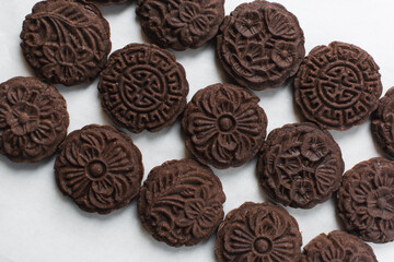 Overhead view of stamped chocolate cookies on a parchment lined baking tray, top view of embossed chocolate sugar cookies on a white background