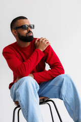 Portrait of stylish african american man in sunglasses sitting on grey background