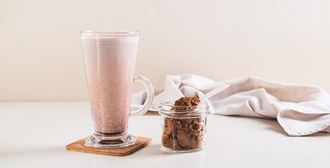 Healthy chocolate protein drink in a glass and powder in a jar on the table web banner