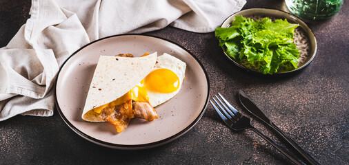 Quesadilla with fried egg, bacon and cheese on a plate on the table web banner