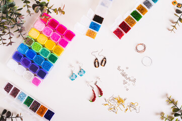 Beautiful beaded earrings, wire, fittings and boxes with colorful beads on the table top view
