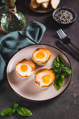 Baked egg and bacon rolls with basil on a plate on a table vertical view