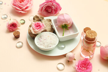 Bottles of cosmetic oil with rose extract and flowers on beige background