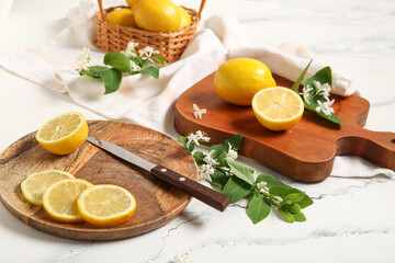 Boards and basket of lemons with blooming branches on white table
