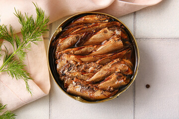 Canned smoked sprats with dill on white tile background