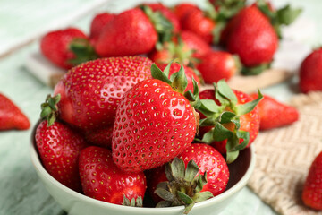 Bowl of fresh strawberries on green wooden background
