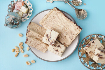Plates with pieces of tasty marble halva and Turkish delight on blue background