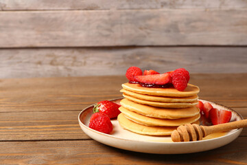 Plate with sweet pancakes and berries on wooden table, closeup