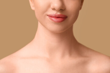 Young woman with beautiful lips on brown background, closeup