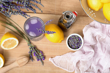 Glass of fresh lavender lemonade with flowers and lemons on wooden table