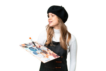 Young artist girl holding a palette over isolated chroma key background looking to the side and...