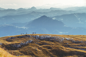 Sechs Wanderer auf einem Bergkamm vor blauen Bergen im Herbst