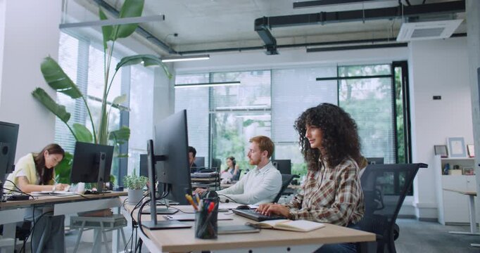 Group of busy managers working in spacious office. People entering text on keyboards and looking at displays. Concentrating on working process. Workplace. Business concept. Development.
