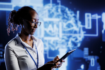 African american admin writes code on tablet to visualize artificial intelligence neural networks using augmented reality. High tech workspace supervisor runs AI script for information processing