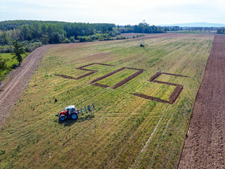 A giant SOS, a symbolic call against excessive land use, written into the ground by a tractor.