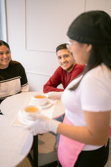 Waitress serving tea to couple smiling at coffee shop