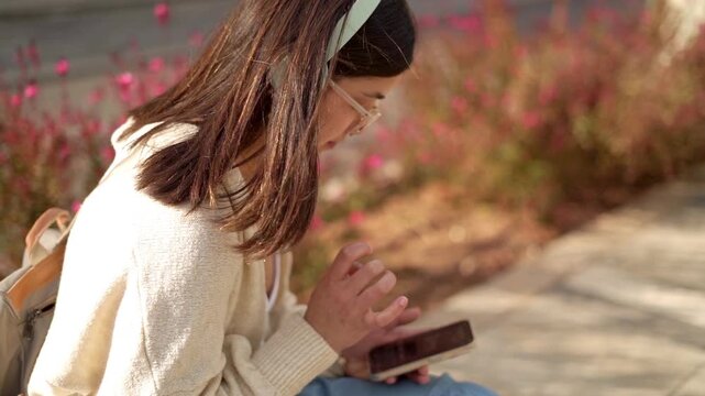 A young woman, focused intensely on her phone, having an OCD episode while seated outdoors