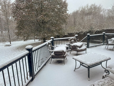 Snow falling and collecting on deck furniture during the day - Powered by Adobe