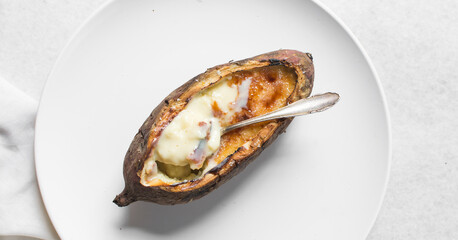 Overhead view of sweet potato crème brûlée on a white plate, top view of a sweet potato filled with creme brulee