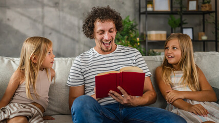 Adult caucasian father read a book, fairytale to his daughters
