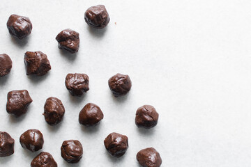 Overhead view of chocolate cookies dough on a parchment lined baking tray, top view of chocolate sugar cookie dough on a white background