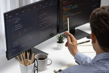 IT developer man pointing information on laptop screen at back side view, thinking program update analyzing website online to create interesting approaching web page data at modern office. Postulate.