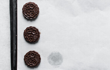 Overhead view of stamped chocolate cookies on a parchment lined baking tray, top view of embossed chocolate sugar cookies on a white background