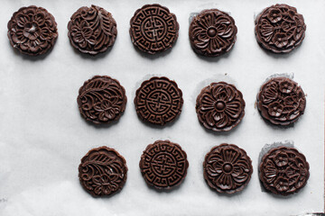 Overhead view of stamped chocolate cookies on a parchment lined baking tray, top view of embossed chocolate sugar cookies on a white background