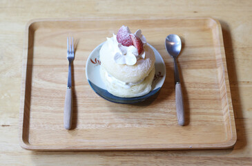 bowl of donut cream with strawberries and spoon on wooden table.