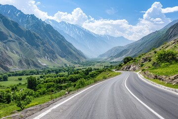 Fototapeta premium A winding mountain road stretches through a valley with towering mountains in the background