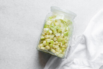 Overhead view of apple cheong in a glass jar on a white background, top view of korean apple cheong in a transparent jar, apple in sugar syrup, process of making apple cheong