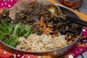 Indian vegan platter consisting  of seasoned rice, mushroom curry, lentil and eggplant curry, flatbread and salad.