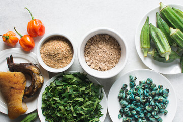 Overhead view of ingredients for making ogbono soup on a granite countertop, top view of mise en place of ingredients for making ogbono and okro soup, process of making nigerian ogbono soup