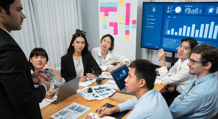 Diverse group of business analyst team analyzing financial data report. Finance data analysis chart and graph dashboard show on TV screen in meeting room for strategic marketing planning. Habiliment
