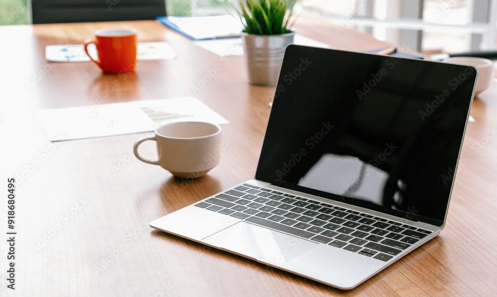Poster laptop computer with opened lid on table in meeting room of office workspace. uds