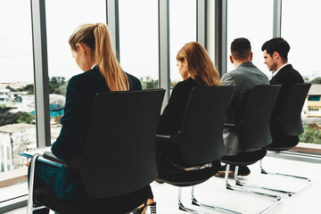 Businesswomen and businessmen waiting on chairs in office for job interview. Corporate business and...