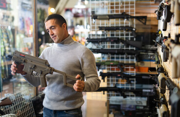 Man chooses semi-automatic pneumatic assault rifle at a gun store