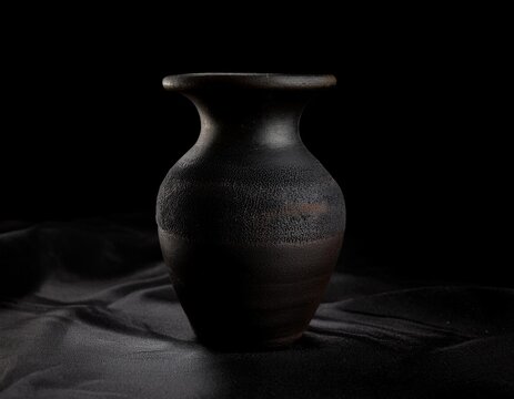 Vajilla de barro y adornos con fondo negro y telas con iluminaci&oacute;n tenue